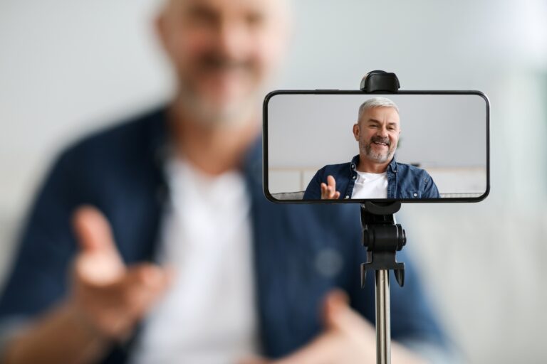 Mobile phone screen with cheerful senior man blogger